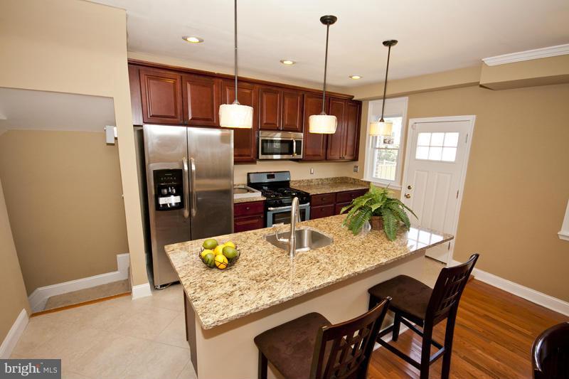 811 Wicklow Road Baltimore, MD 21229 - Photo 13 of 30 a kitchen with stainless steel appliances granite countertop sink stove refrigerator and wooden floor