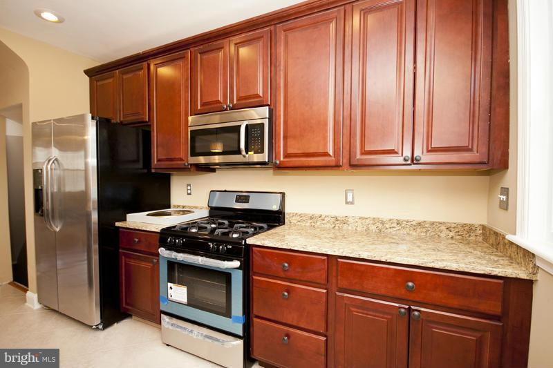 811 Wicklow Road Baltimore, MD 21229 - Photo 9 of 30 a kitchen with granite countertop wooden cabinets stainless steel appliances and a window