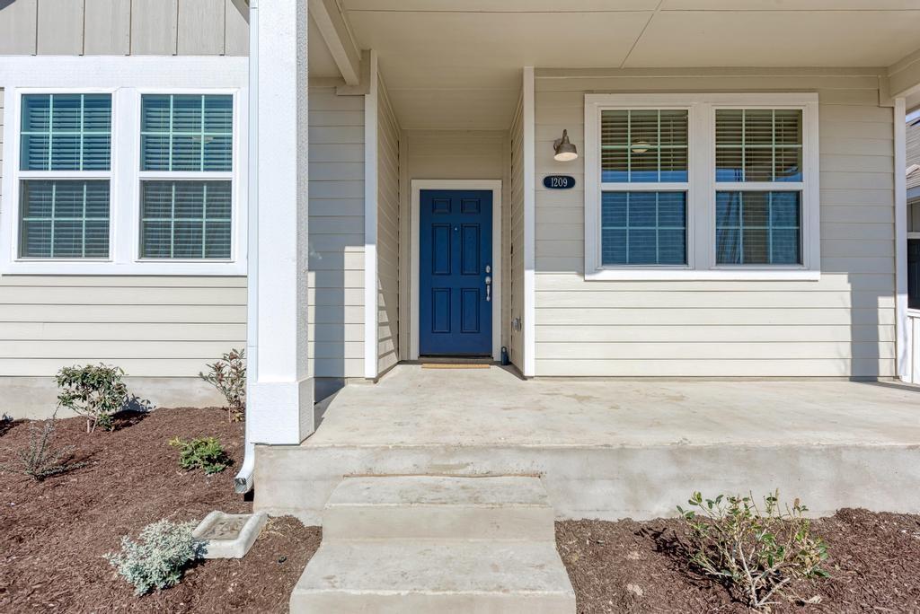 1209 Goforth Road Kyle, TX 78640 - Photo 4 of 32 A welcoming entry features a bold blue door, concrete steps, and a charming front porch.