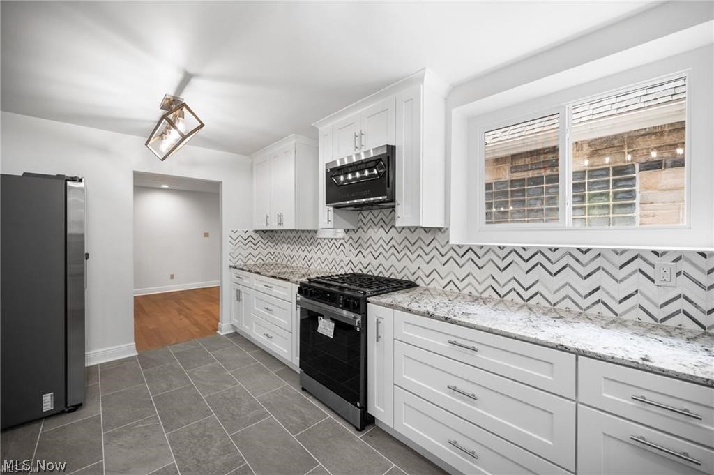 28300 Aurora Road Solon, OH 44139 - Photo 4 of 36 Kitchen featuring white shaker-style cabinetry, a chevron-patterned tile backsplash, and light-toned countertop surfaces