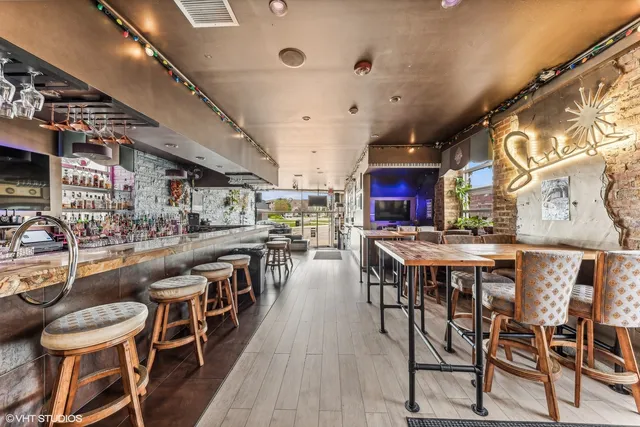 a dining hall with stainless steel appliances kitchen island granite countertop a dining table chairs and a large window