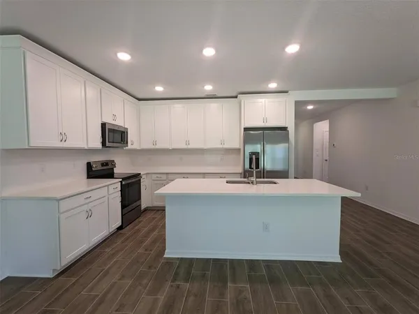 a view of kitchen with microwave stove refrigerator and cabinets