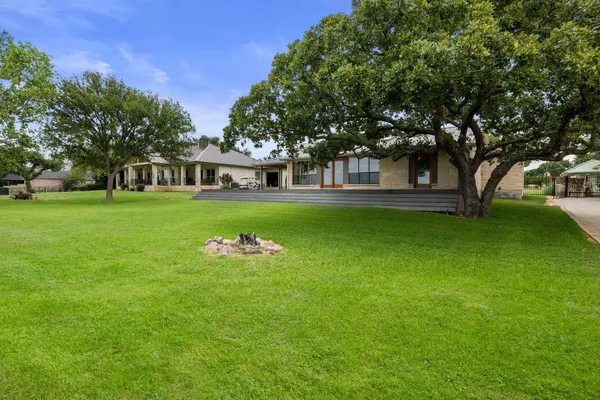 a view of a house with a big yard and large trees