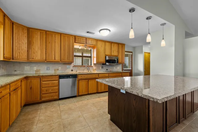 a kitchen with stainless steel appliances granite countertop a sink a counter space and cabinets