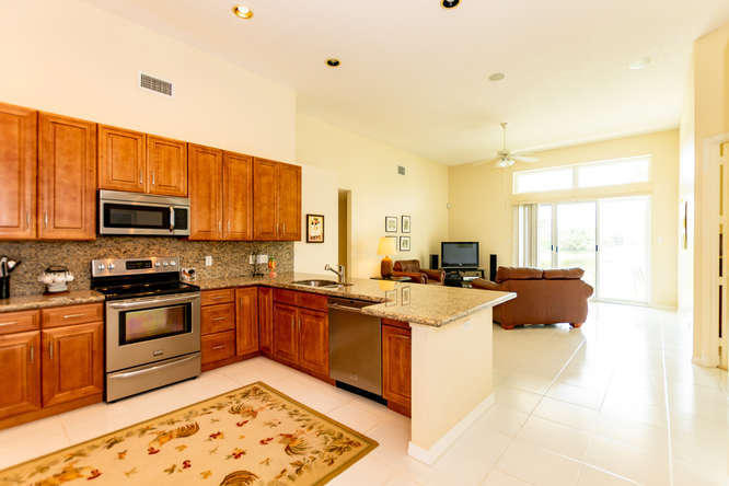 19627 Dinner Key Drive Boca Raton, FL 33498 - Photo 10 of 46 a kitchen with stainless steel appliances granite countertop a stove top oven a sink dishwasher a dining table and chairs with wooden floor
