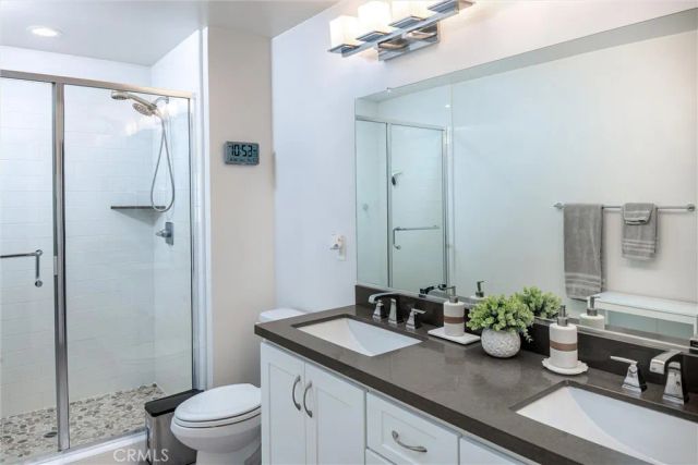 a bathroom with a granite countertop sink a toilet a mirror and shower