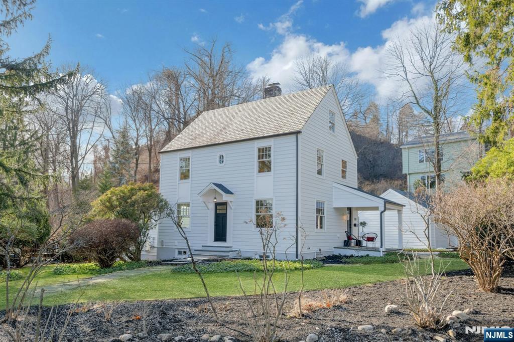 a view of a white house with a big yard and large trees