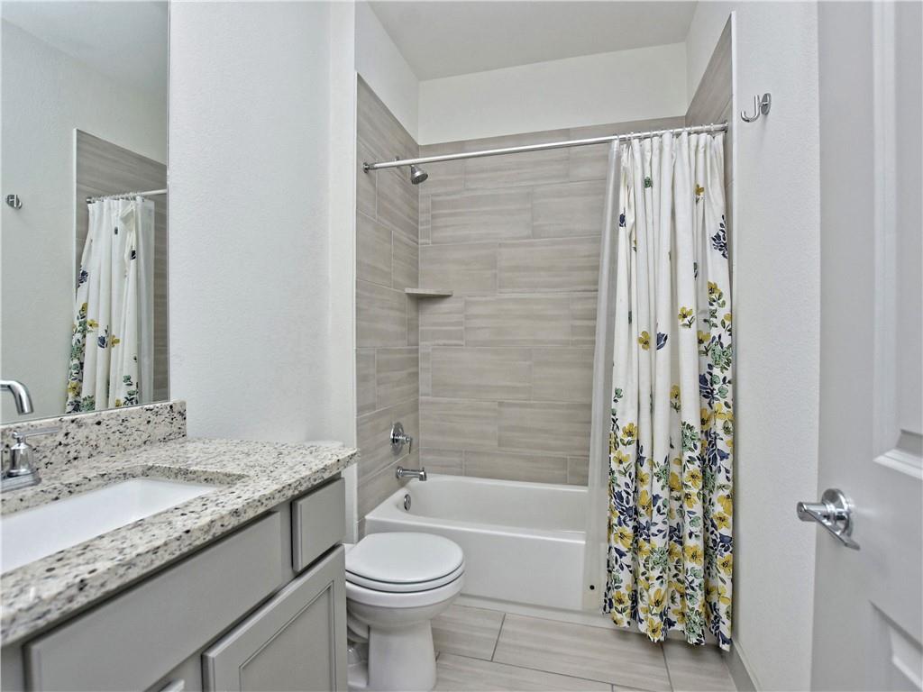 2172 Local Rebel Street Leander, TX 78641 - Photo 17 of 24 a bathroom with a granite countertop bathtub shower sink vanity mirror and toilet