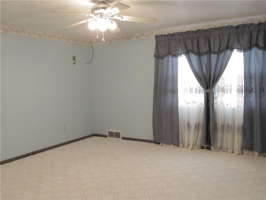 717 Blue Ridge Road Pittsburgh, PA 15239 - Photo 14 of 25 an empty room with a chandelier fan and windows