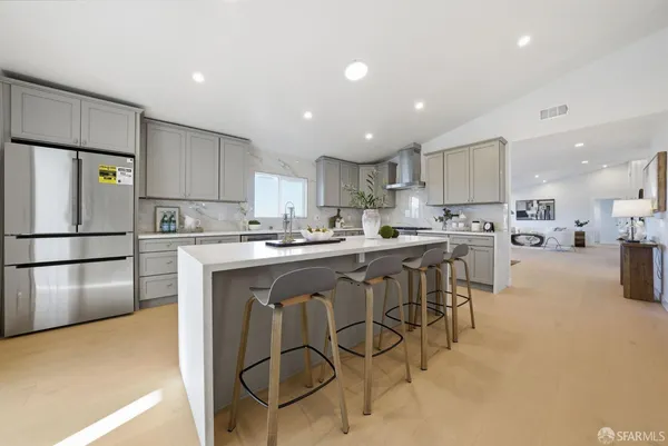 a kitchen with stainless steel appliances granite countertop a sink a stove a refrigerator and white cabinets with wooden floor