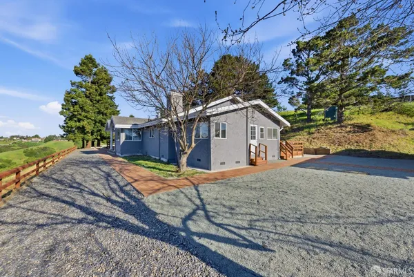 a view of a white house with large windows and palm tree