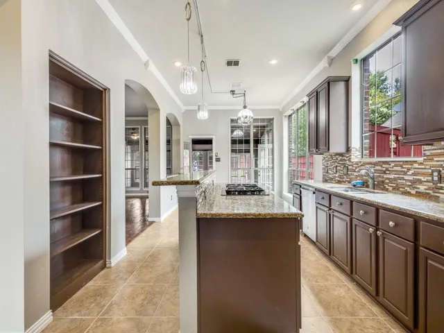 a large kitchen with kitchen island a large counter top stainless steel appliances and cabinets