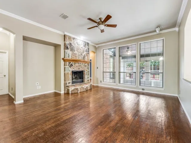 an empty room with wooden floor fan and windows