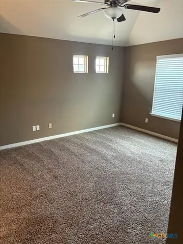 an empty room with a window and a ceiling fan