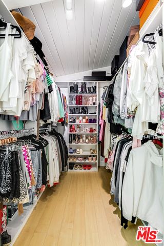 a view of walk in closet with clothes and shoes