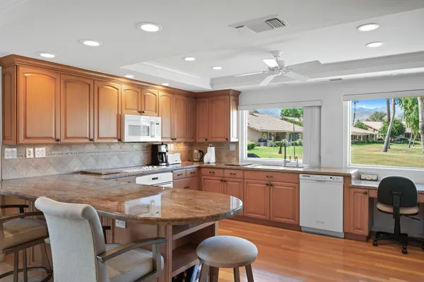 a kitchen with granite countertop wooden floor cabinets dining table and chairs