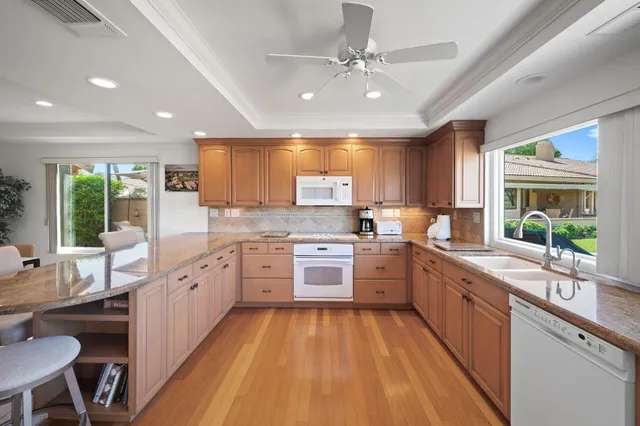 a large kitchen with stainless steel appliances granite countertop a stove refrigerator a sink dishwasher a dining table and chairs with wooden floor