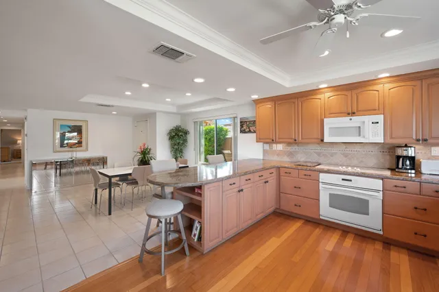 a large kitchen with cabinets chairs and wooden floor