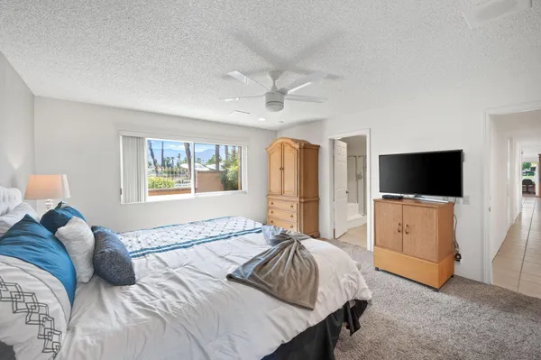 a spacious bedroom with a bed and a flat screen tv