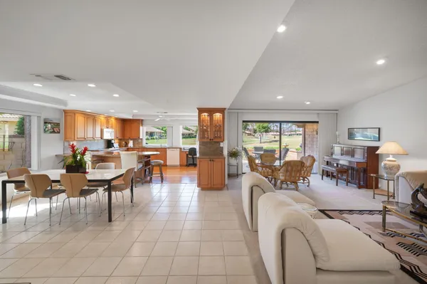 a living room with furniture large window and kitchen view