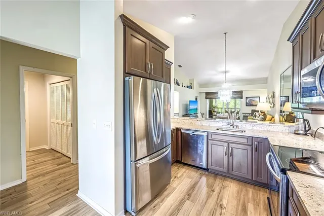 a kitchen with stainless steel appliances granite countertop a refrigerator a sink and a stove with wooden floor