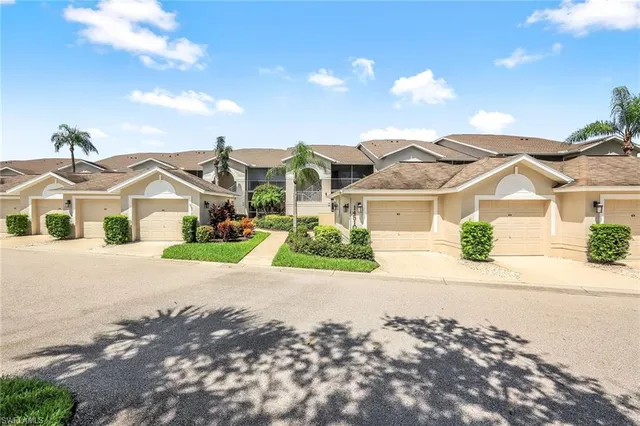 a view of a white house with a yard and potted plants