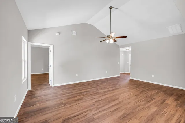 a view of a room with wooden floor a ceiling fan and windows
