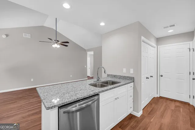 a kitchen with stainless steel appliances granite countertop a sink and a wooden floor