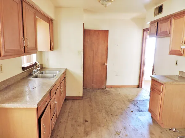 a kitchen with a sink stove top oven and wooden floor