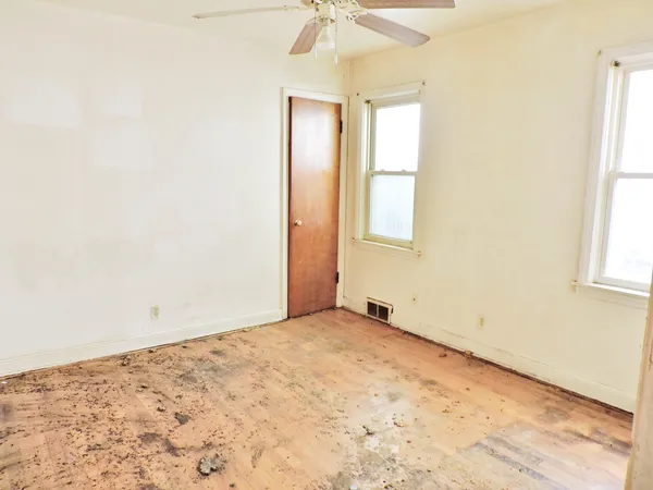 an empty room with a window and a chandelier fan