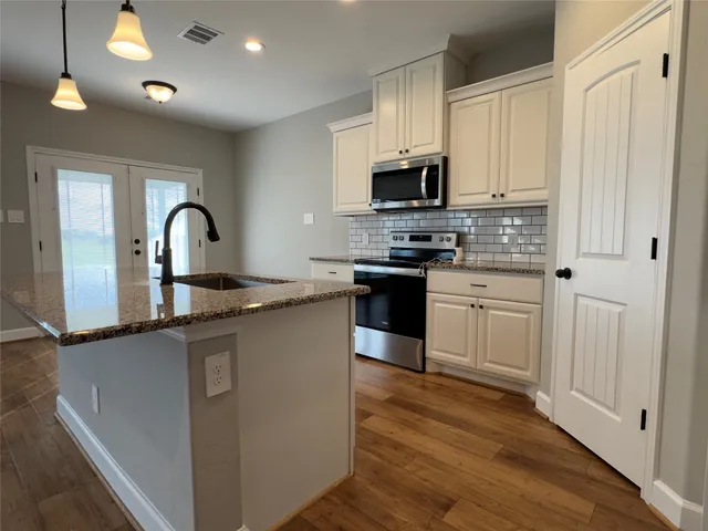 a kitchen with stainless steel appliances granite countertop a stove top oven a sink a counter space and cabinets