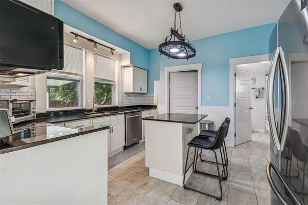 a kitchen with stainless steel appliances granite countertop a sink a stove a refrigerator cabinets and dining table