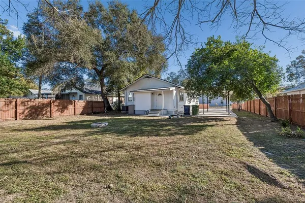 a view of house with outdoor seating and trees in the background