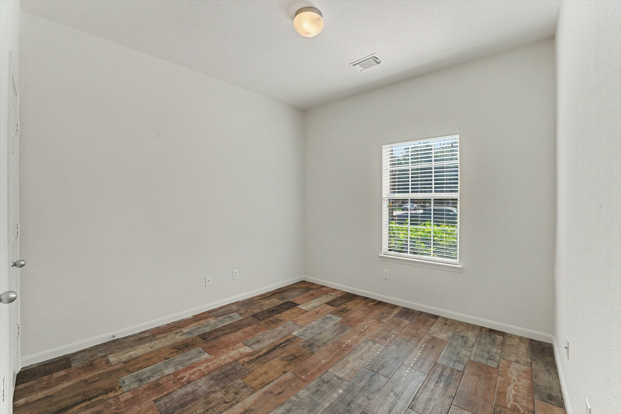 21427 Blooming Rock Lane Spring, TX 77379 - Photo 15 of 32 This room features neutral walls, a single window with blinds for natural light, and rustic-style wood flooring, creating a cozy and inviting space.