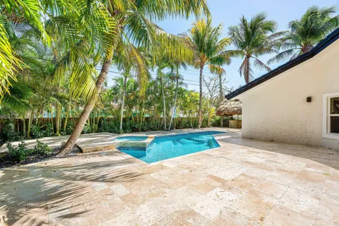 a view of swimming pool with a yard and palm trees