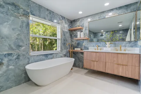 a bathroom with a granite countertop sink mirror and bathtub