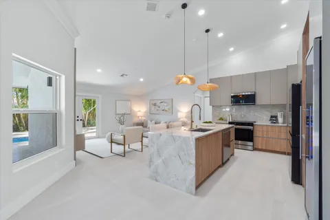 a large kitchen with kitchen island a large counter top space a sink stainless steel appliances and cabinets