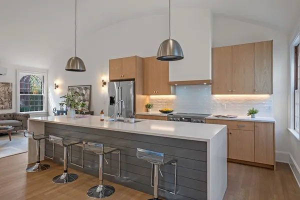 a kitchen with kitchen island granite countertop a sink a stove and chairs