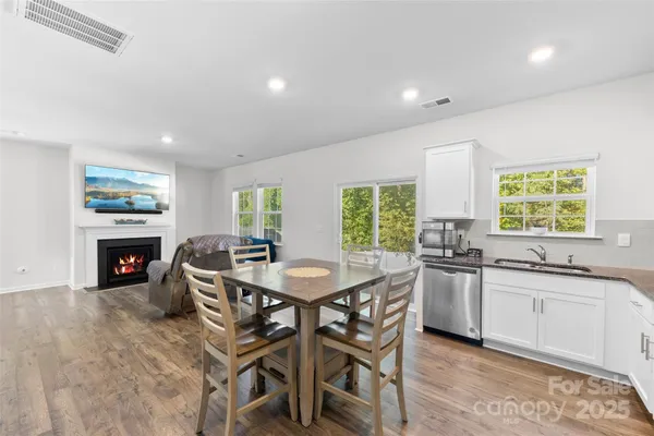 a kitchen with granite countertop a sink a stove a dining table and chairs