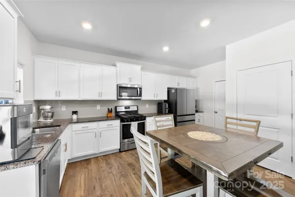 a kitchen with stainless steel appliances a sink a stove a refrigerator cabinets and a dining table