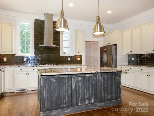 a kitchen with stainless steel appliances granite countertop a sink a stove a refrigerator cabinets and wooden floor
