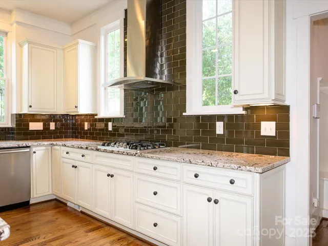 a kitchen with granite countertop white cabinets and a window