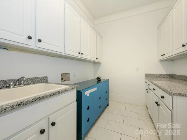 a kitchen with granite countertop white cabinets and a sink