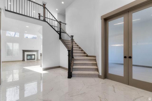 2724 Mt Jordan Road Sandy, UT 84092 - Photo 8 of 33 Stairs featuring french doors, a high ceiling, a premium fireplace, recessed lighting, and marble tiled floors