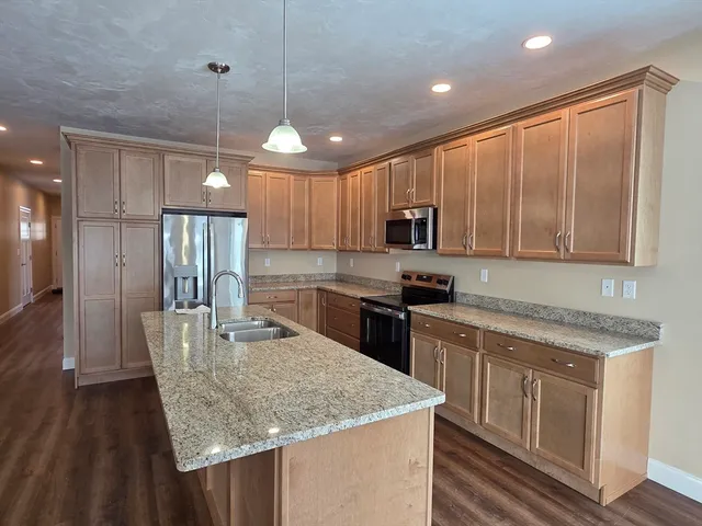 a kitchen with stainless steel appliances granite countertop a sink refrigerator and cabinets