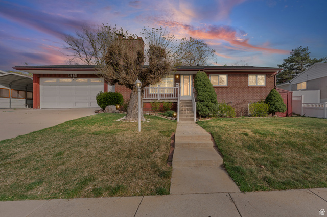 Ranch-style home with a front lawn, concrete driveway, an attached garage, brick siding, and a porch