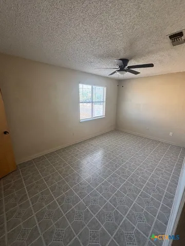 an empty room with windows and fan