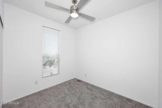 an empty room with windows and fan