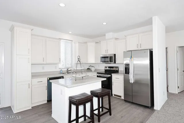 a kitchen with a refrigerator a sink dishwasher a stove and white cabinets with wooden floor