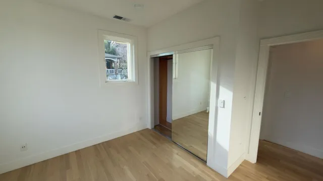 an empty room with wooden floor front door and windows
